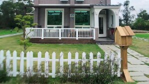 Una casa a due piani con una recinzione bianca a stecche, un portico e una cassetta delle lettere.