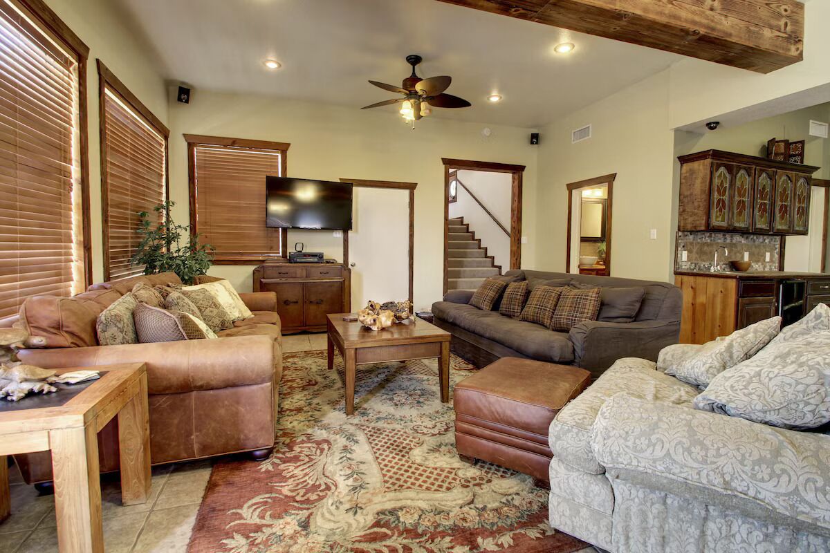 A spacious living room with leather sofas, a wooden coffee table, and a large rug.