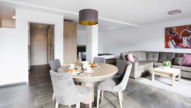 A modern living room with a round dining table, grey upholstered chairs, a grey sofa, and a coffee table. - Modern apartment with sophisticated equipment (Montabaur)