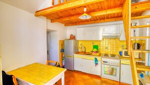 Una cocina compacta con vigas de madera, un refrigerador, una estufa y un microondas.