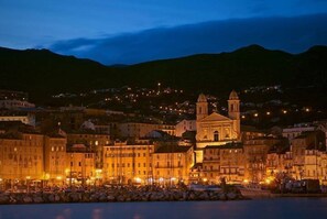 A coastal town at dusk with illuminated buildings and a prominent church.