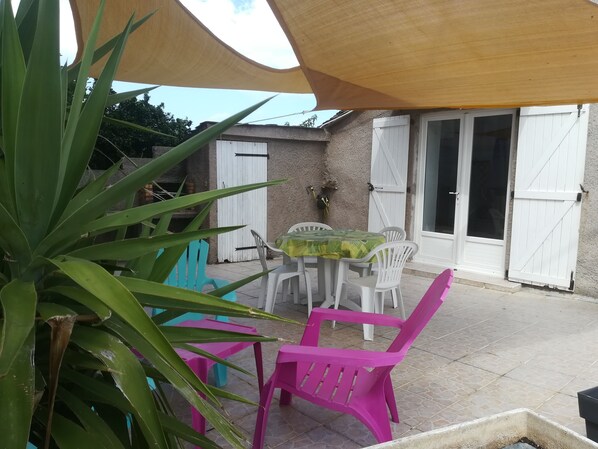 A patio with a table and chairs, a white door, and a covered area.