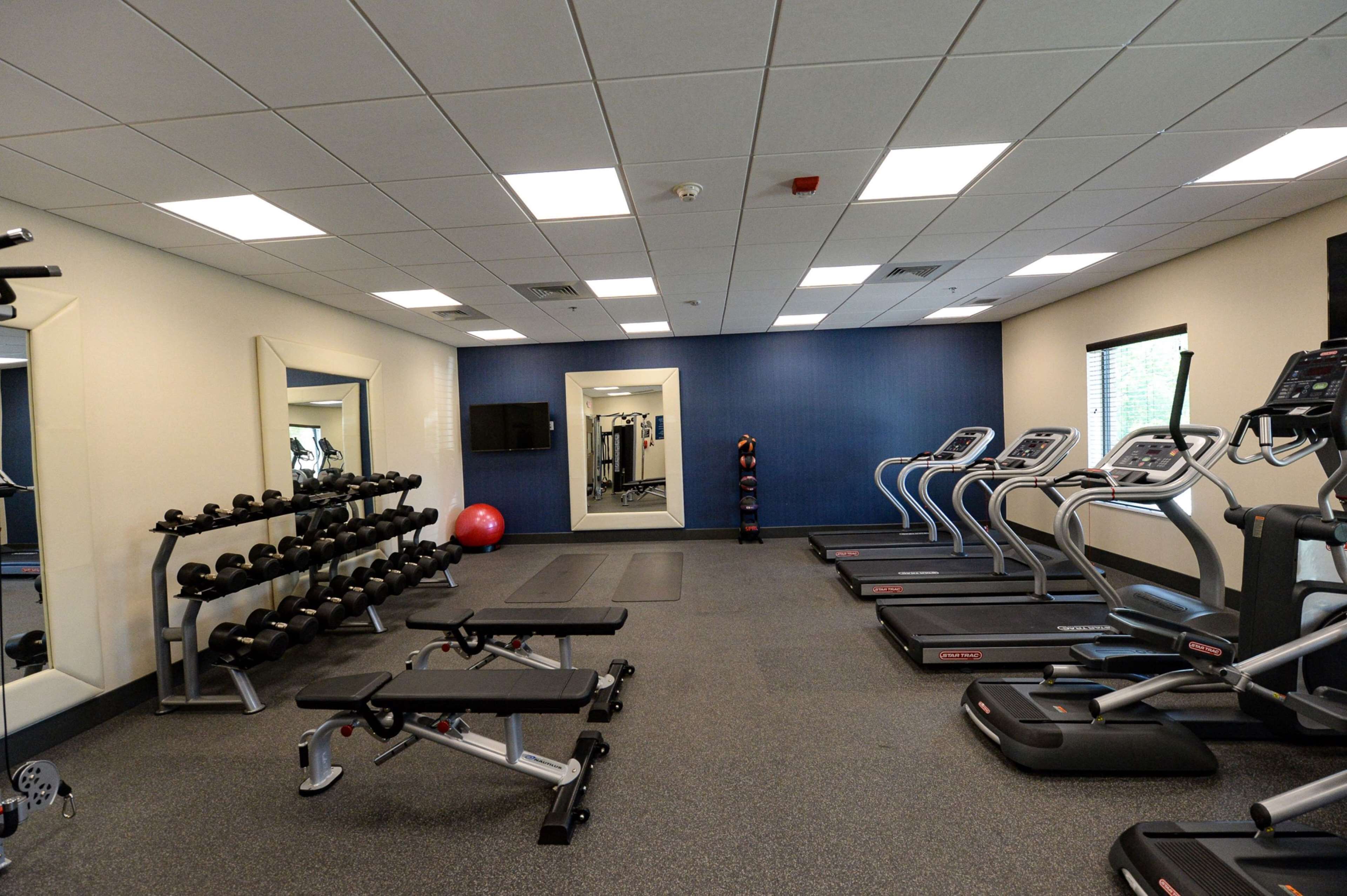 A gym with treadmills, weight benches, and a mirror.