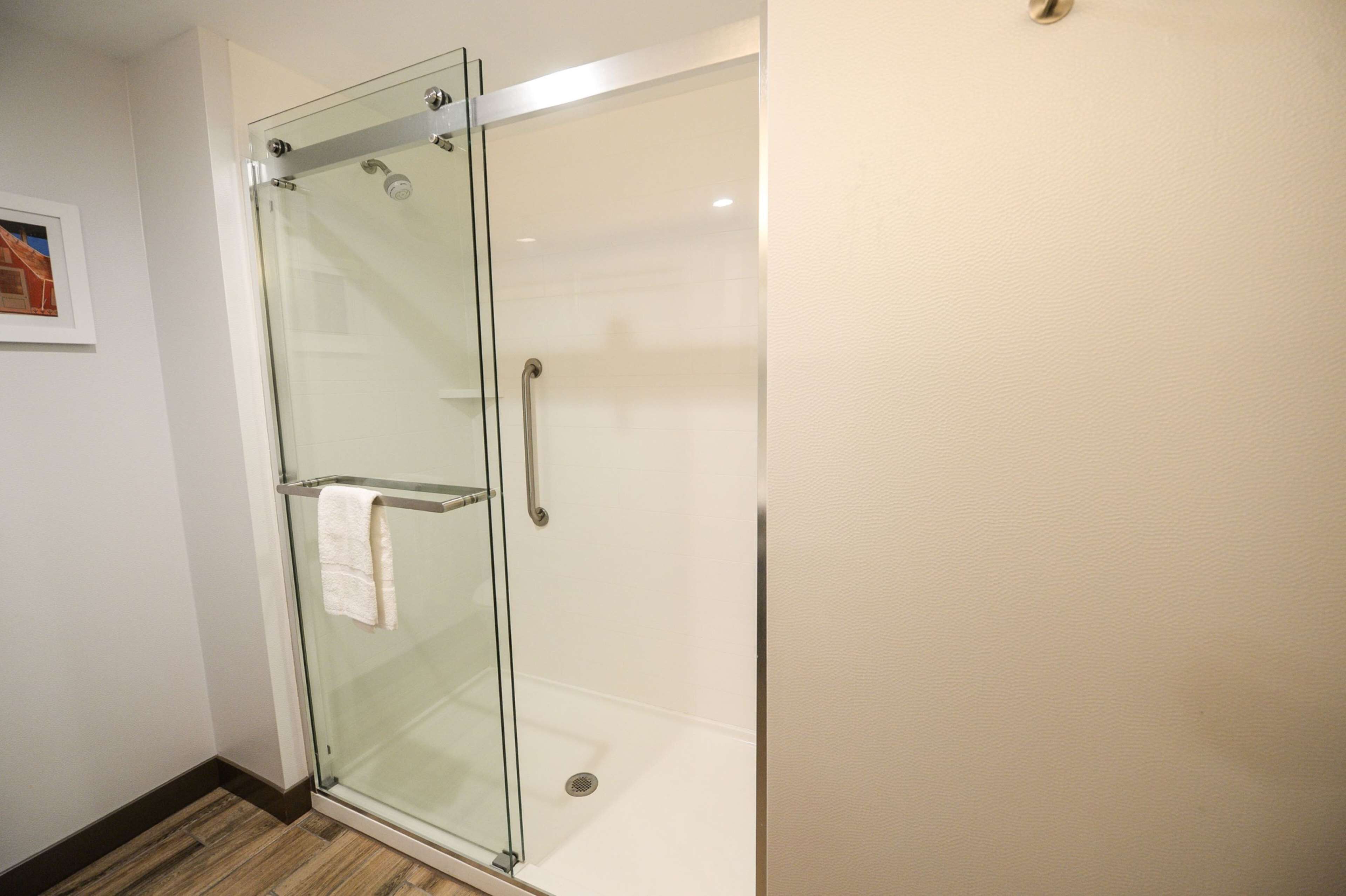 A glass-enclosed shower with a towel hanging on the door handle.