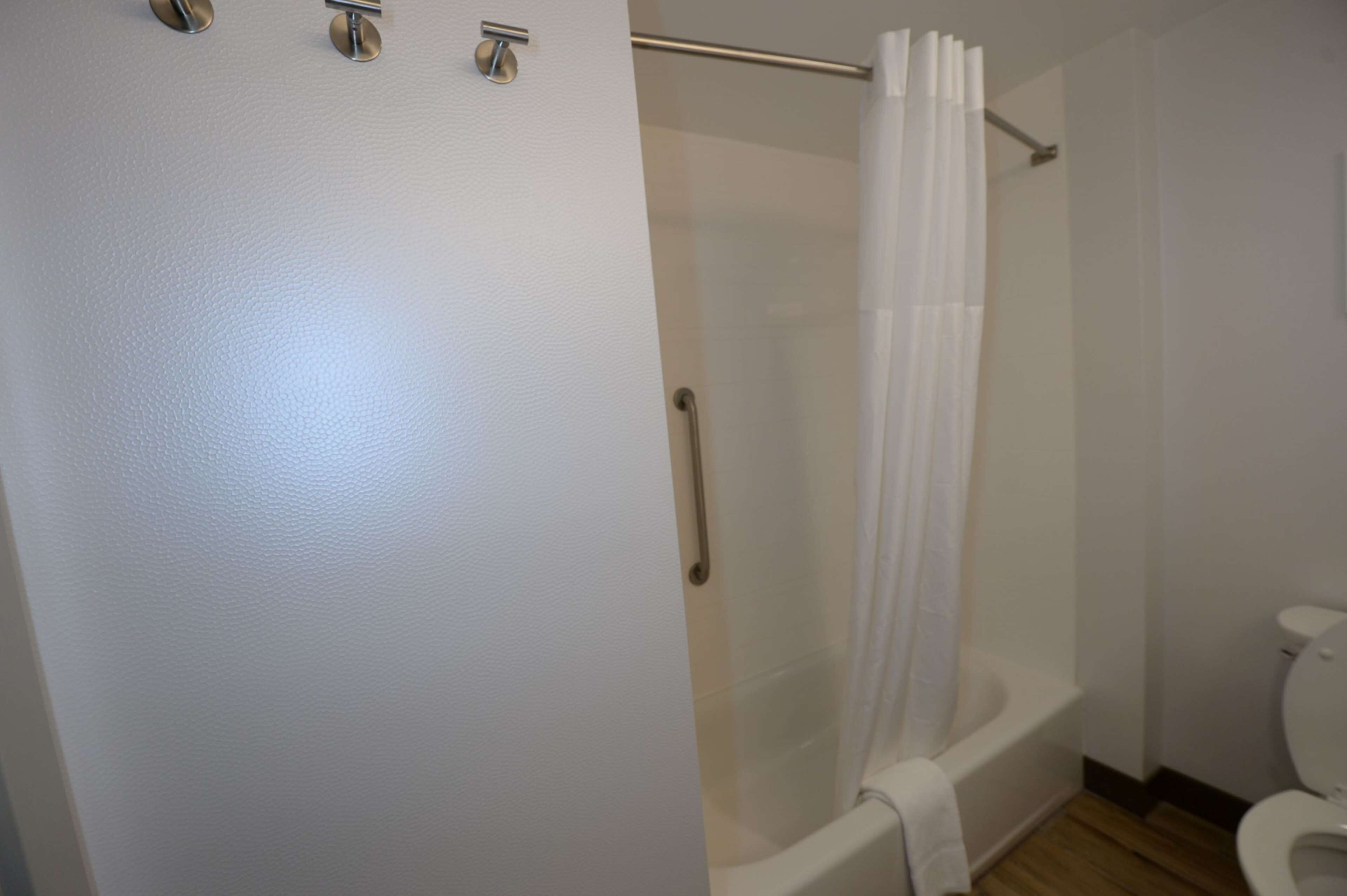 Un baño con ducha envuelta en vidrio, bañera blanca y un inodoro.