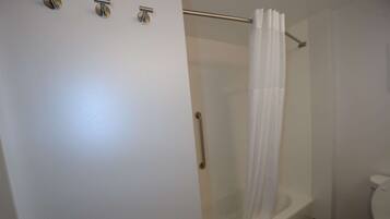 Un baño con ducha envuelta en vidrio, bañera blanca y un inodoro.