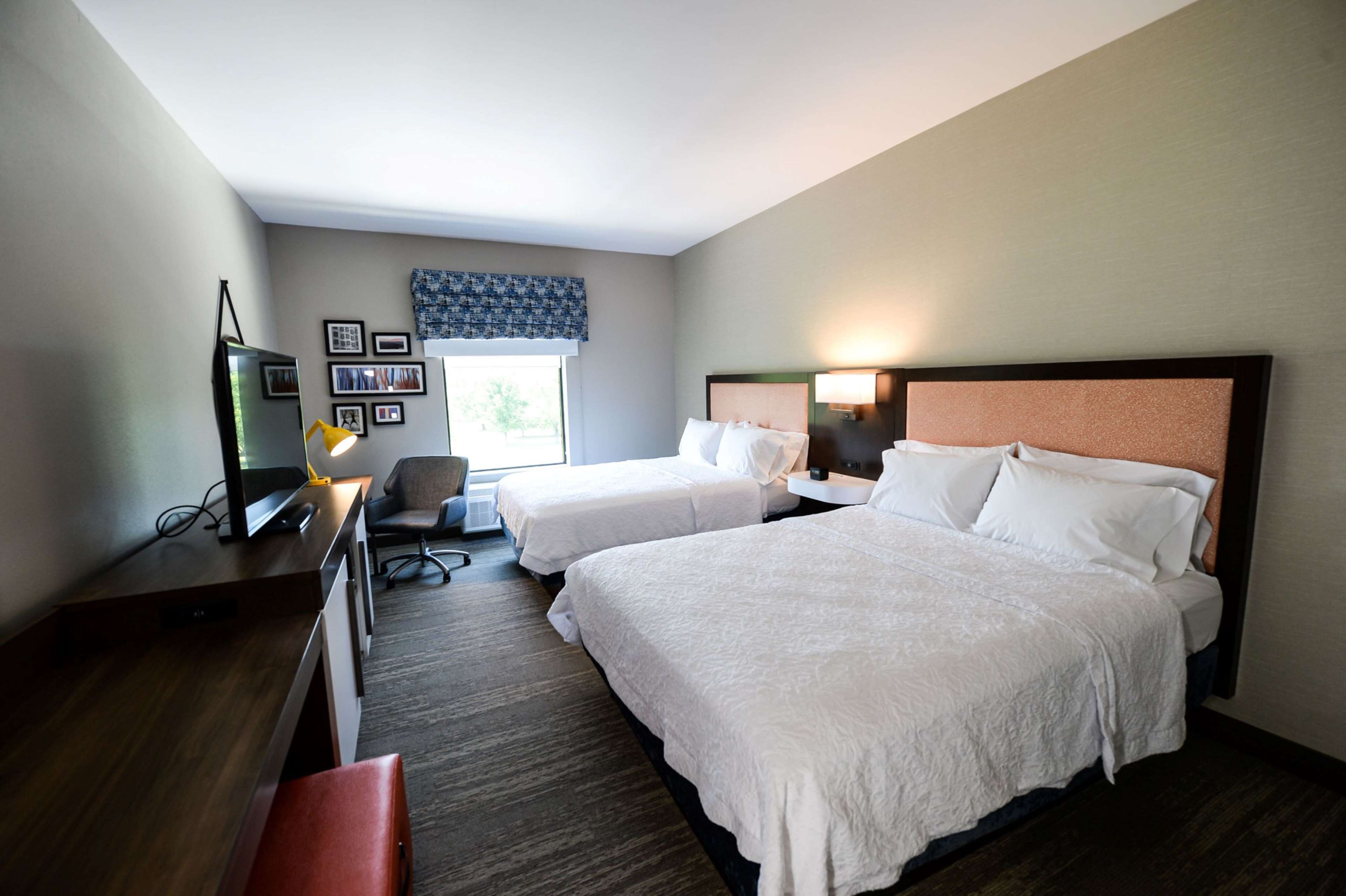 Una habitación de hotel con dos camas, un escritorio, una silla y un televisor.