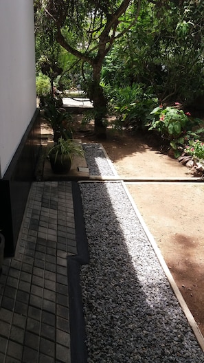 A pathway leading to a garden area with a mix of gravel and potted plants. - Green Corridor - Ahangama (Ahangama)