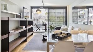 A modern living room with a dining area, featuring a sofa set, a coffee table, and a bookshelf. - 3 rooms 6 persons in Sant Gervasi with terrace near the Teknon  (barcelona)