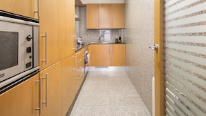 A narrow kitchen with wooden cabinets and a granite countertop. - 3 rooms 6 persons in Sant Gervasi with terrace near the Teknon  (barcelona)