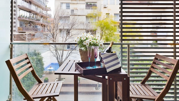 A balcony with a table and two chairs, a bottle of champagne, and a vase of flowers. - 3 rooms 6 persons in Sant Gervasi with terrace near the Teknon  (barcelona)