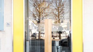 A hostel entrance with a yellow sign stating "True Hostel for Special People" and a glass door. - Hi Go Hostel & Suites (Vila Nova de Famalicao)