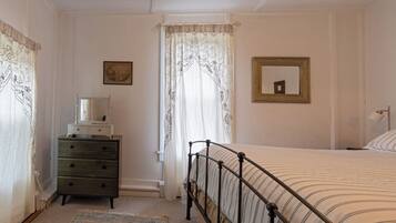 A bedroom with a bed, a dresser, a mirror, and a rug.