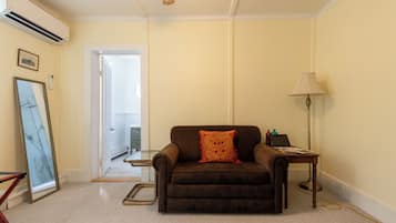 A room with a brown sofa, a standing lamp, and a framed picture on the wall.