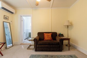 A room with a brown sofa, a standing lamp, and a framed picture on the wall. - The Woodbine Inn (Palenville)