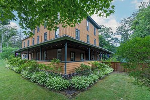A two-story building with a covered porch and a landscaped garden. - The Woodbine Inn (Palenville)