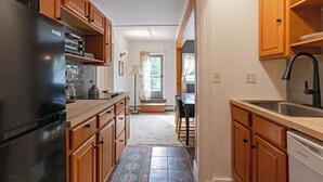 A kitchen with wooden cabinets, a black refrigerator, and a dishwasher. - The Woodbine Inn (Palenville)