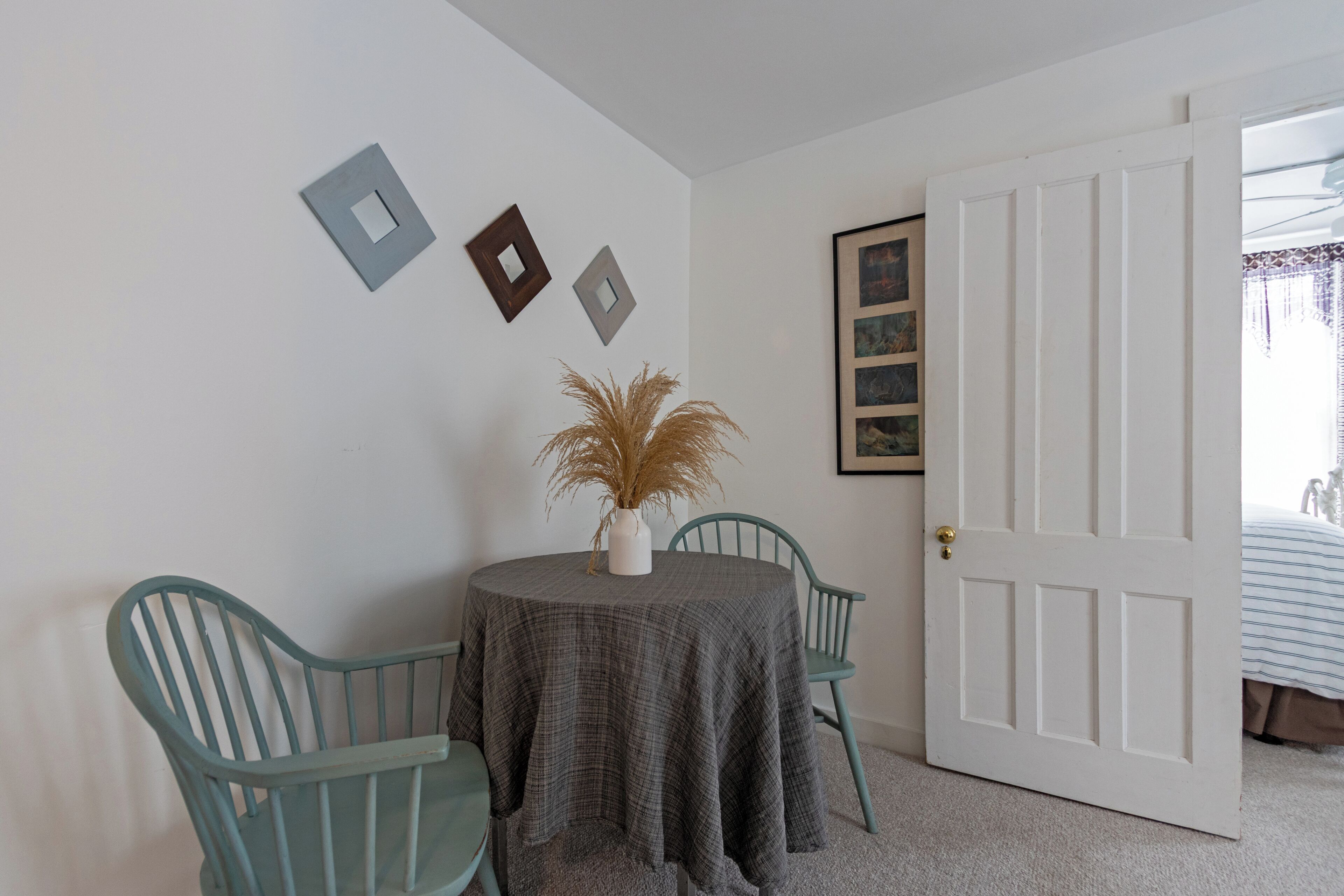 Une pièce avec une table ronde, deux chaises, une porte et des éléments décoratifs sur les murs.