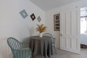 A room with a round table, two chairs, a door, and wall decorations. - The Woodbine Inn (Palenville)