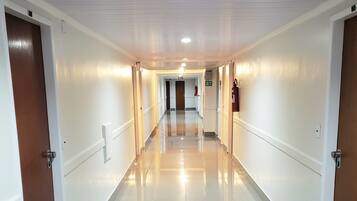 A long, well-lit hallway with white walls and doors on both sides.