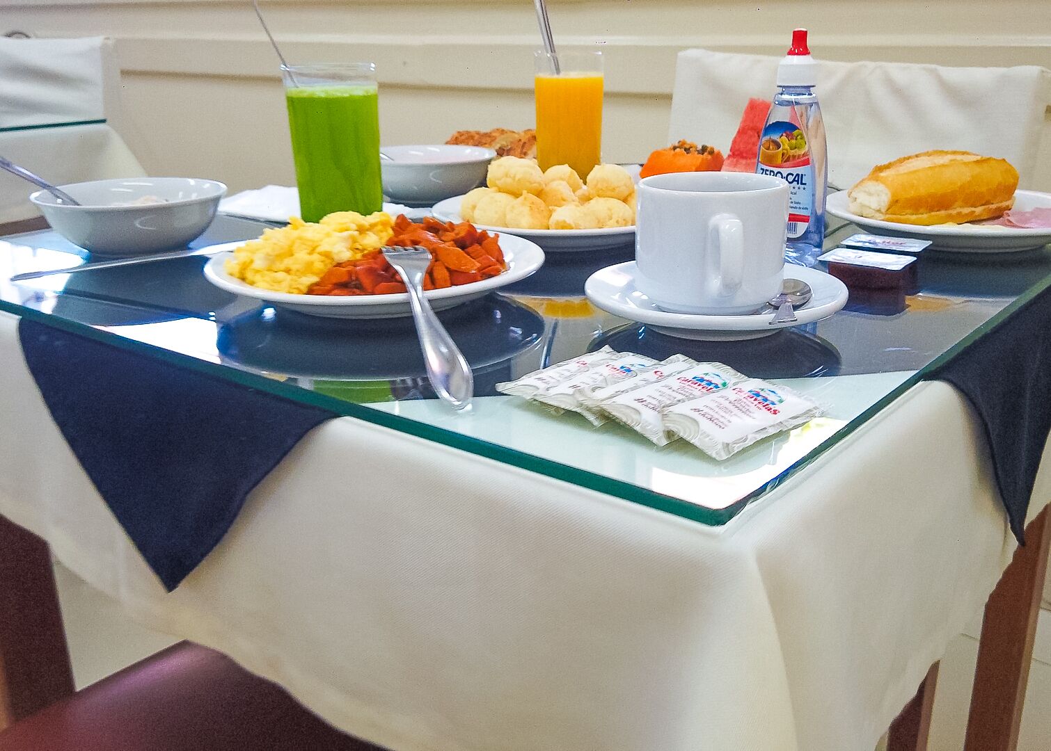 A breakfast table with various dishes, drinks, and condiments.