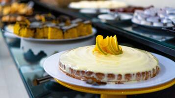 Un bufé con diversos postres, incluyendo un pastel con cobertura amarilla y glaseado blanco.