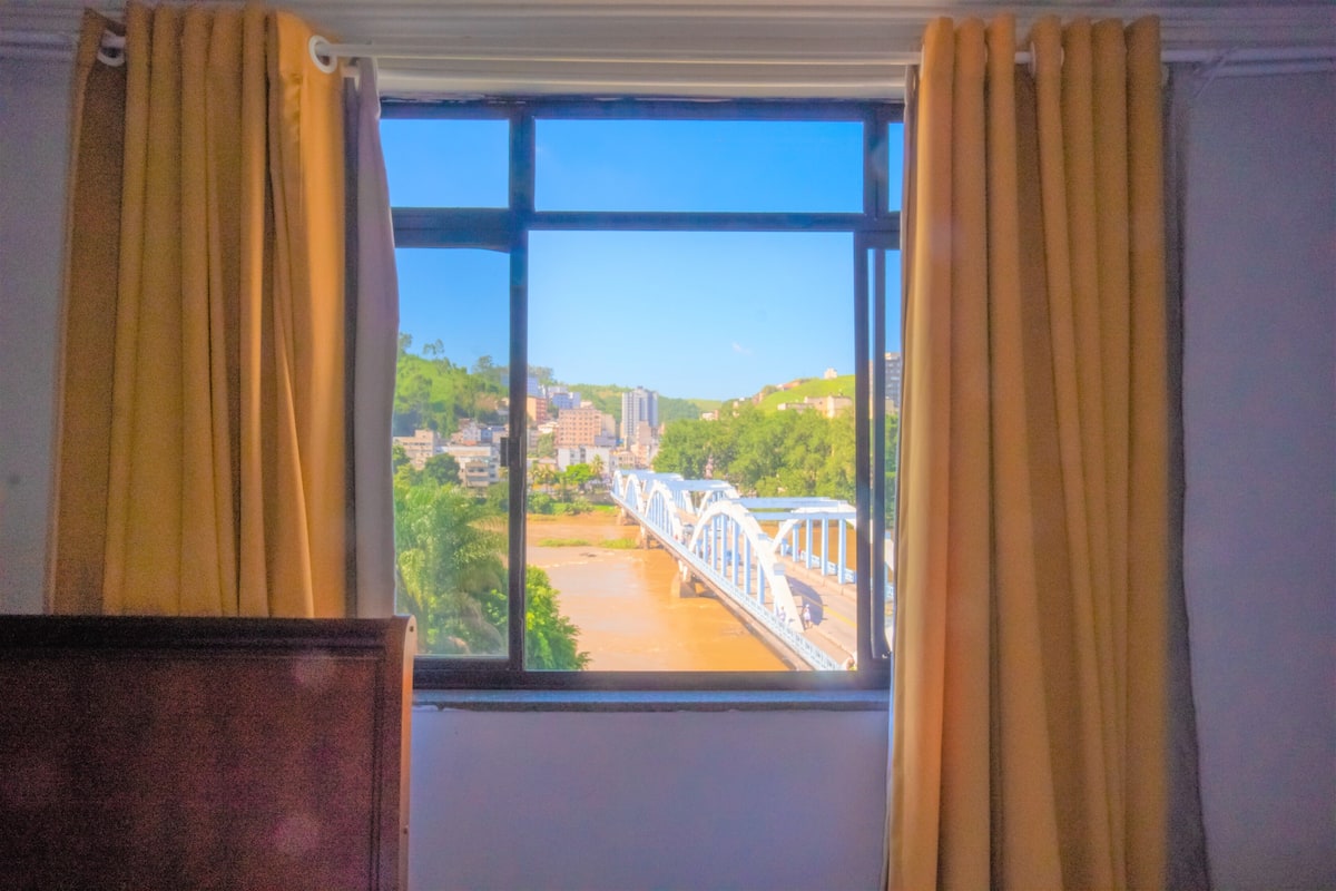 Una habitación con ventana que da a un puente y un río.