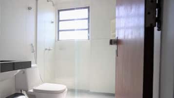 Un baño con inodoro, ducha y ventana.