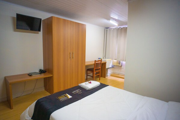 Una habitación de hotel con cama, escritorio, silla y armario.