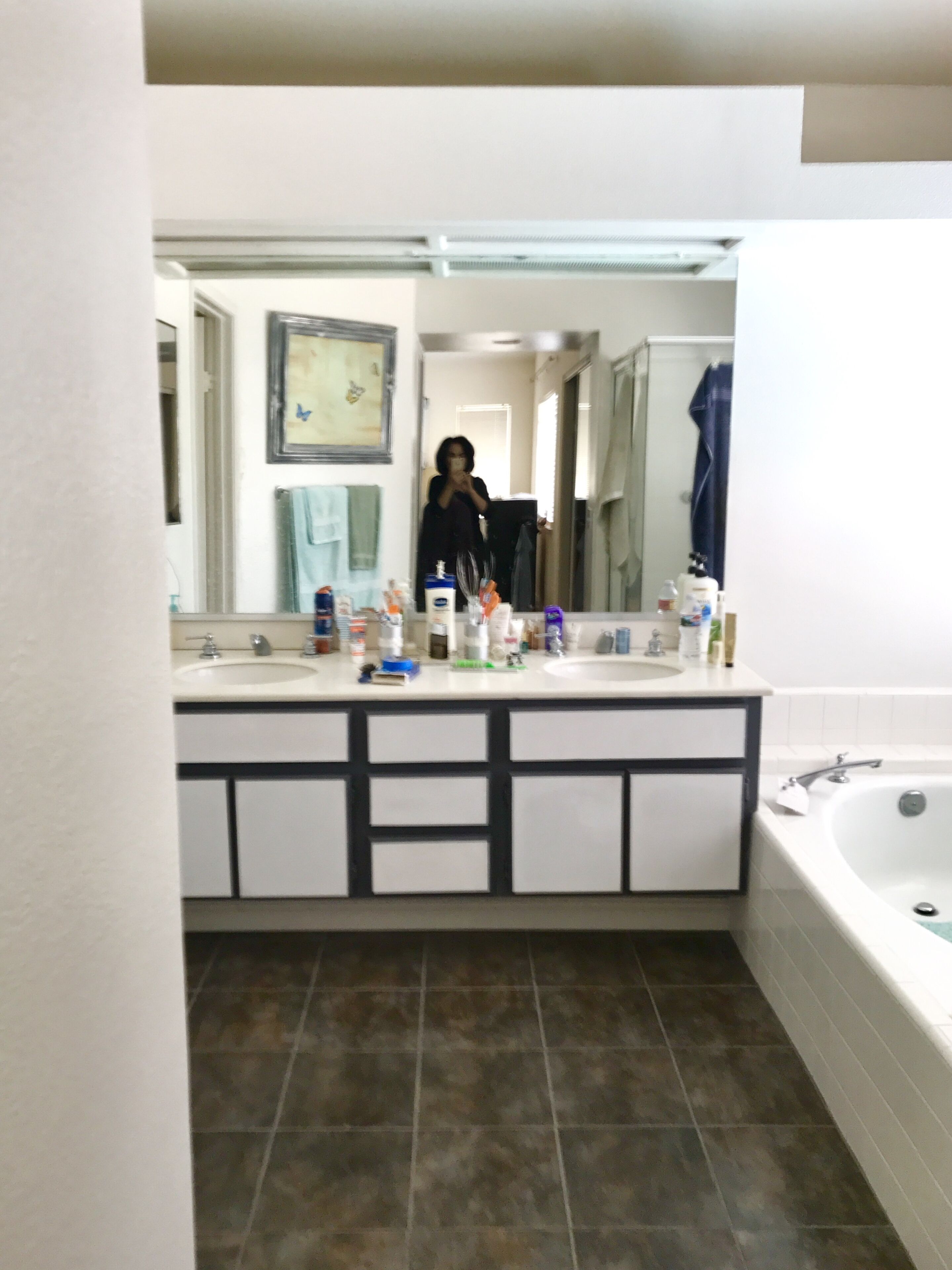 Ein Badezimmer mit großem Spiegel, doppelter Waschtisch und Badewanne.