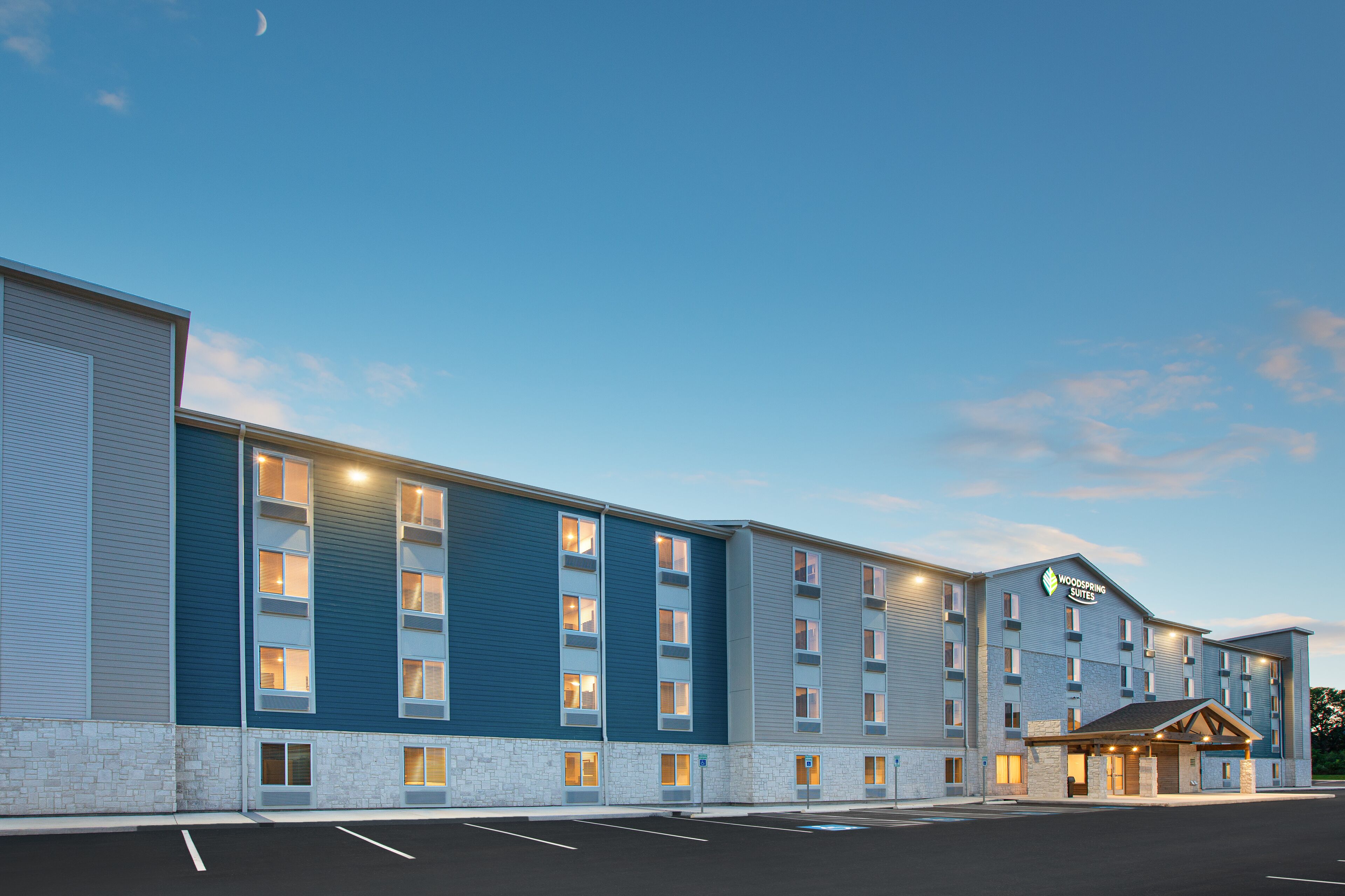 Ein mehrstöckiges Hotel mit auffälliger Beschilderung, einem Parkplatz und blauem Himmel.