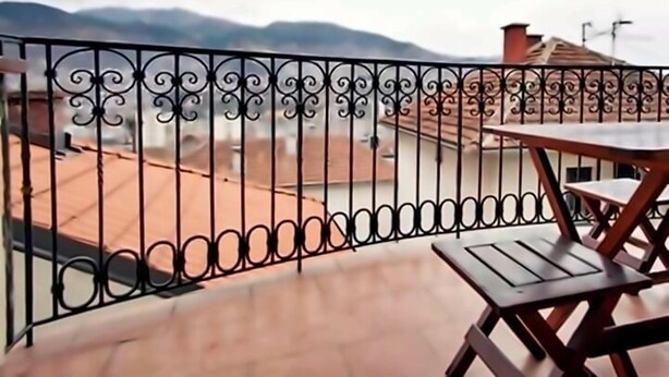 A balcony with a wrought iron railing, a wooden table, and a view of mountains. - Beautiful apartment in center Sarajevo (Sarajevo)