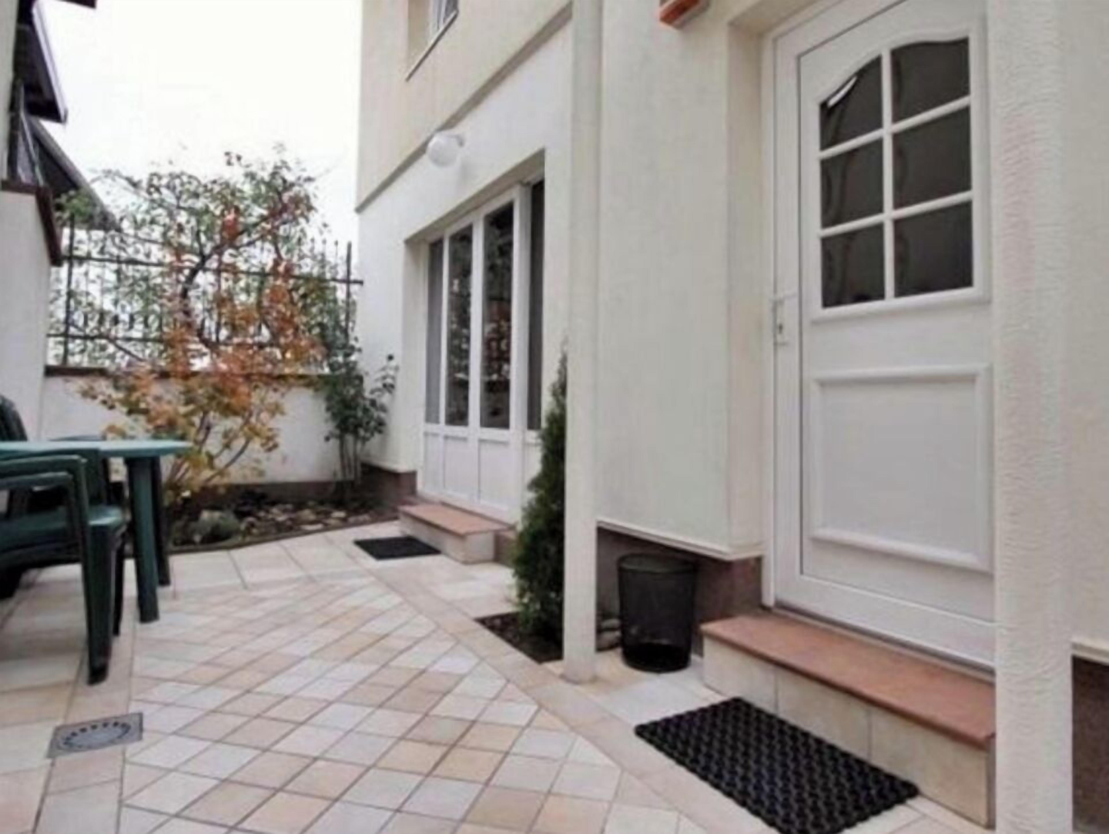 A small, enclosed patio area with a tiled floor, a door, and a window.