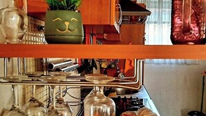 A kitchen with a wooden shelf holding various items including a bottle, a plant, and a jar. - Beautiful apartment in center Sarajevo (Sarajevo)