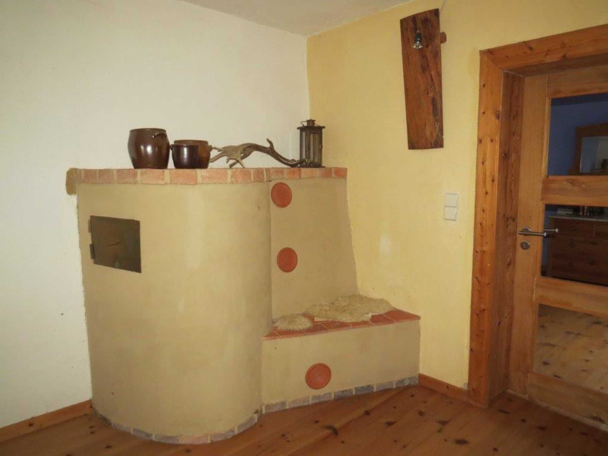 Una habitación de esquina con chimenea integrada, una puerta de madera y un pequeño estante con adornos.