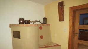 A corner room with a built-in fireplace, a wooden door, and a small shelf with decorative items.