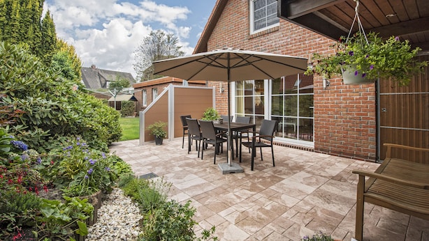 Une terrasse avec une table et des chaises, une plante suspendue et un banc en bois.
