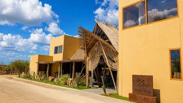 Un resort con una estructura de techo de paja, un cartel que indica 'Vacation Wayna Beach' y un cielo despejado.
