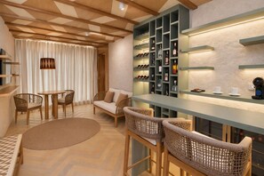 A modern bar area with a wooden ceiling, a seating area with a sofa and chairs, and a wine rack with bottles. - Hotel Wayira Beach by On vacation (Manaure)
