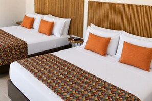 Two twin beds with white linens and orange pillows, a patterned bedspread, and a wooden headboard. - Hotel Wayira Beach by On vacation (Manaure)
