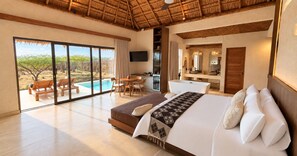 Un dormitorio con una cama grande, baño, comedor y vista a una piscina y árboles.