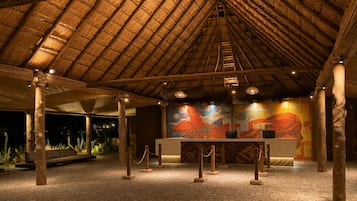 Un espacio interior con techo de paja, una recepción y una pared de mosaicos.