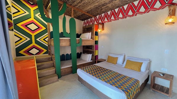 Una habitación con una cama litera, un patrón geométrico de colores en la pared, techo de madera y una pequeña mesita de noche.