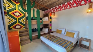Una habitación con una cama litera, un patrón geométrico de colores en la pared, techo de madera y una pequeña mesita de noche.