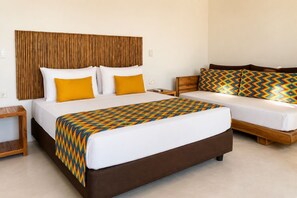 Una habitación de hotel con una cama grande, un sofá más pequeño, un cabecero de madera y una manta decorativa.