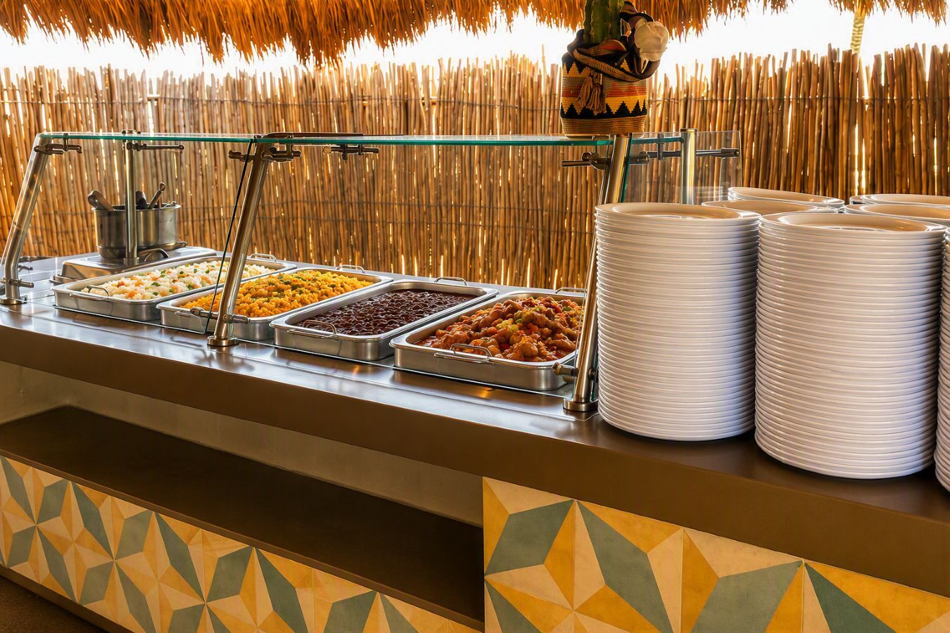 En buffet med flere madfade og stakke af hvide tallerkner.