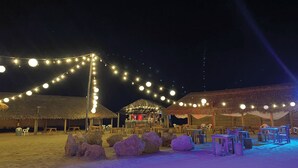 A beachside venue with thatched-roof structures, string lights, and outdoor seating. - Hotel Wayira Beach by On vacation (Manaure)