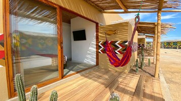 Una habitación con un gran ventanal, piso de madera y una hamaca colgante.