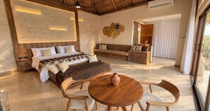 Un dormitorio con cama, sofá, mesa de comedor y un jarrón.