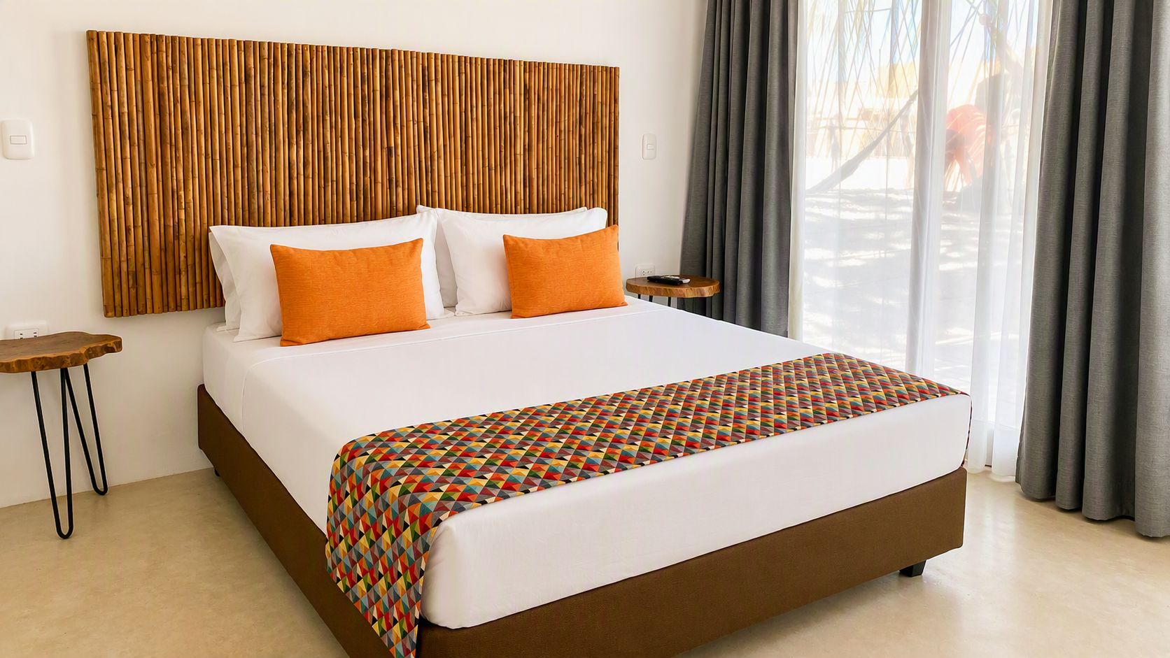 A hotel room with a large bed, a wooden headboard, a small bedside table, and a view of the outdoors.